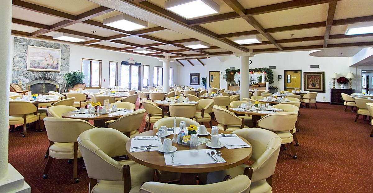 A spacious and well-lit restaurant dining area with neatly arranged tables and comfortable seating.