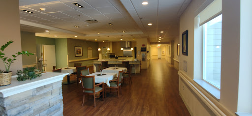 A well-lit dining area with tables and a kitchen in the background.
