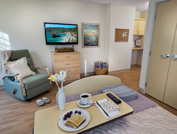 A cozy living room with a set breakfast on the coffee table and a television mounted on the wall.