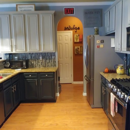 A modern kitchen with light and dark cabinets, stainless steel appliances, and wood flooring.
