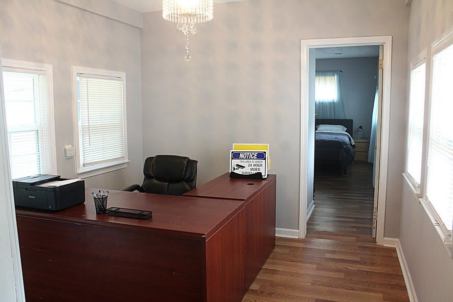A simple office setup with a desk and chair, adjacent to a room.
