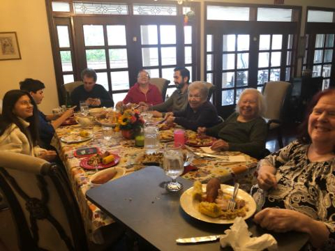 A family gathering around a dinner table, enjoying a meal together.