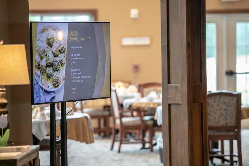 A digital menu displayed near a dining area in a restaurant.