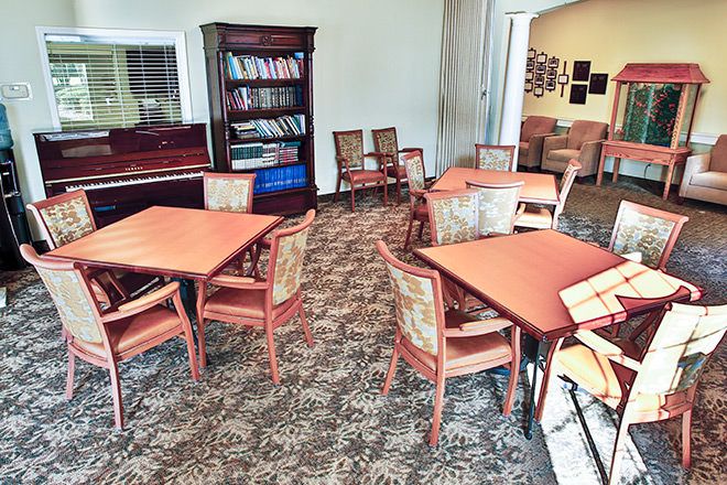 A cozy reading area with tables and chairs alongside a bookshelf filled with books.