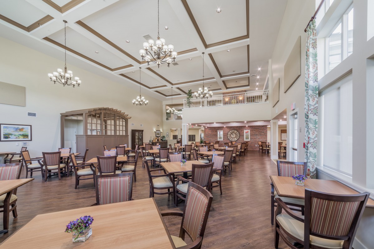 A spacious, elegantly designed dining room with wooden tables and chairs, adorned with chandeliers.
