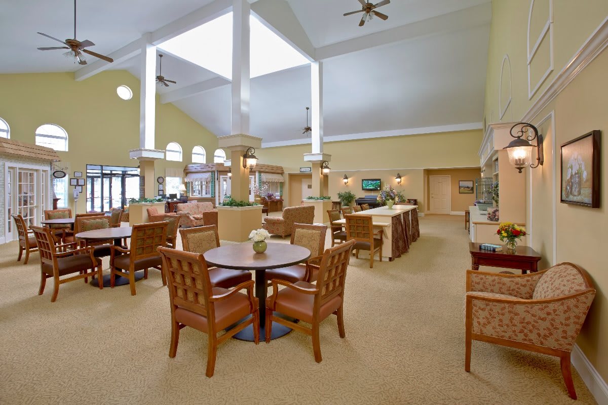 Spacious dining area with multiple tables and chairs, featuring ceiling fans and a bright interior.
