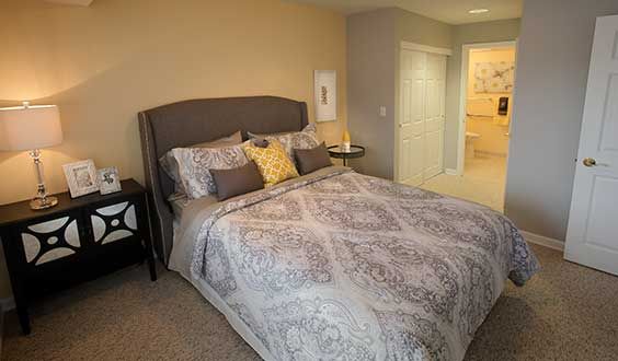 A cozy bedroom featuring a neatly made bed with decorative pillows and a patterned quilt.