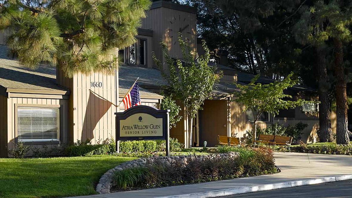 A view of a building with a sign and American flag, surrounded by trees.