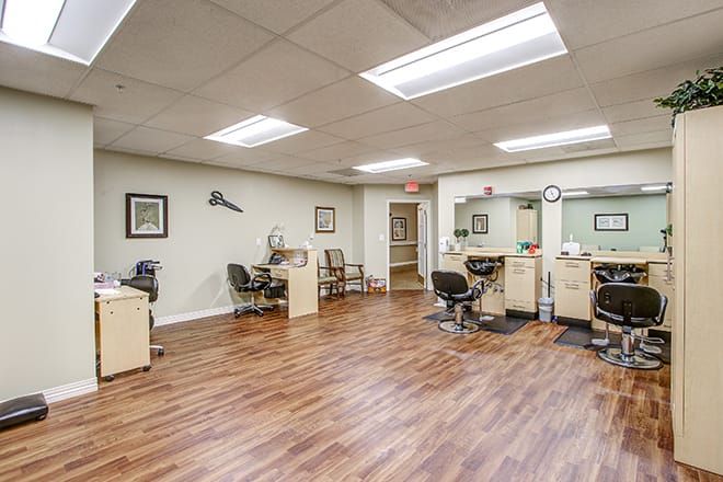 An interior view of a salon with multiple styling stations and wooden flooring.
