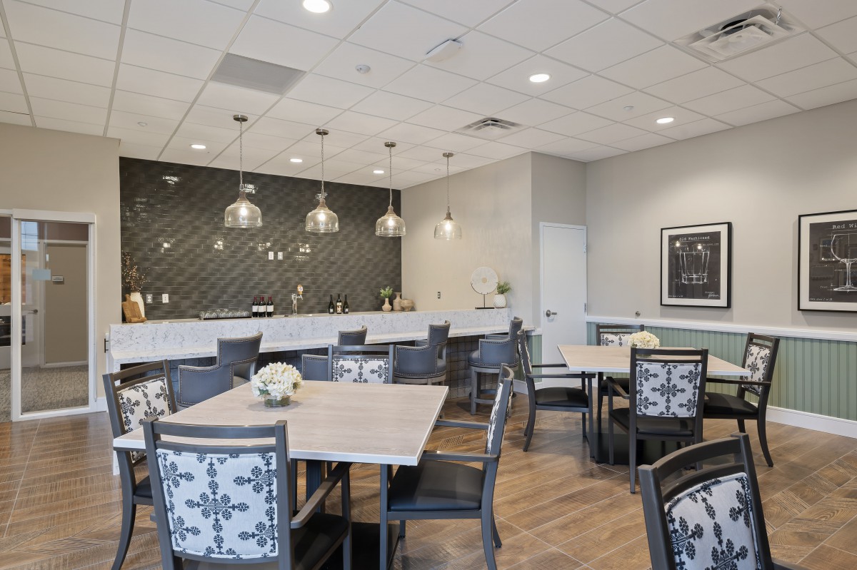 A modern dining area with stylish tables and chairs, featuring pendant lighting and a decorative wall.