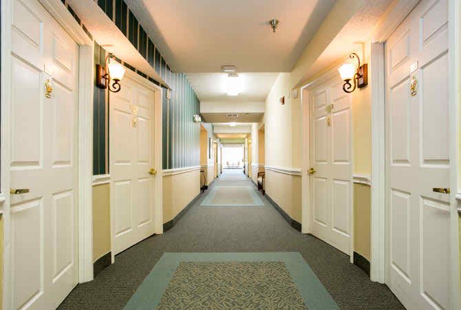 A well-lit hallway with closed doors on either side and carpeted flooring.