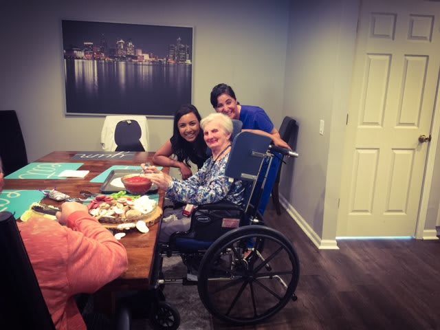 A group of people enjoying a friendly gathering, with one person seated in a wheelchair and others providing care and companionship.