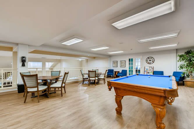A spacious recreation room featuring a pool table and seating area.