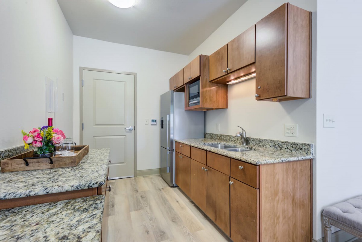 A modern kitchen with wooden cabinets, granite countertops, and stainless steel appliances.