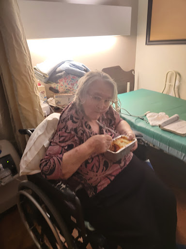 An elderly woman enjoying a meal while seated in her wheelchair.