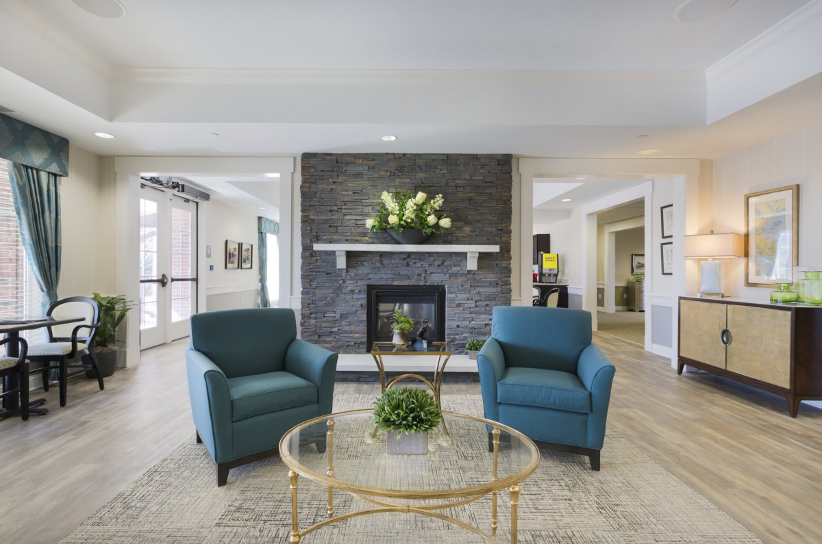 A modern living room with blue armchairs and a central fireplace.
