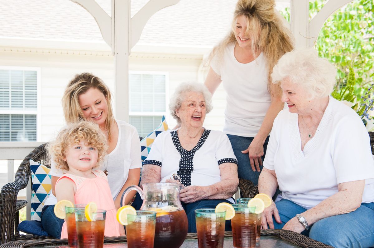 A joyful family gathering outdoors with multiple generations enjoying iced tea together.