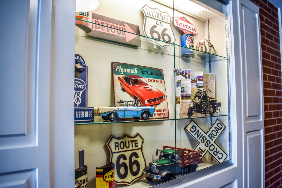 A display case filled with vintage collectibles, featuring Route 66 signs and miniature classic cars.