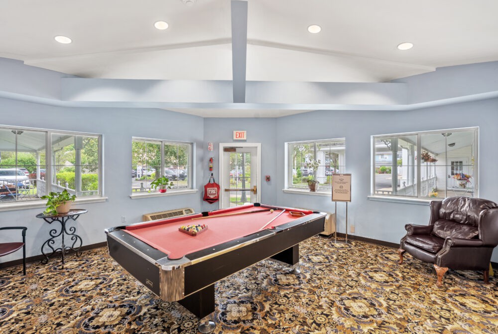 A well-lit game room featuring a pool table and large windows.