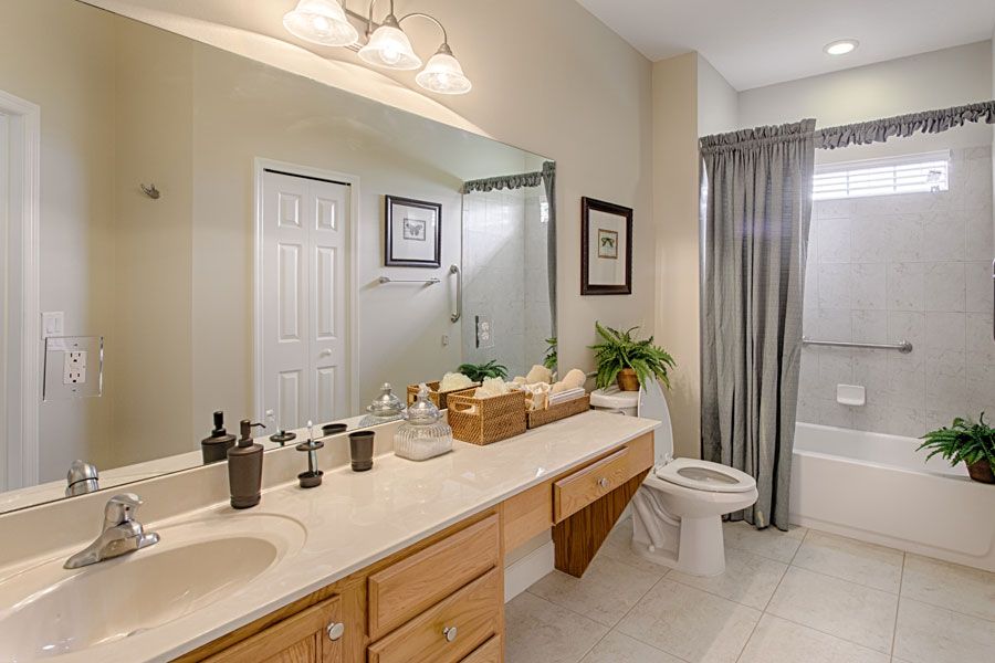 A well-organized bathroom featuring a large mirror, double sinks, and a shower with a curtain.