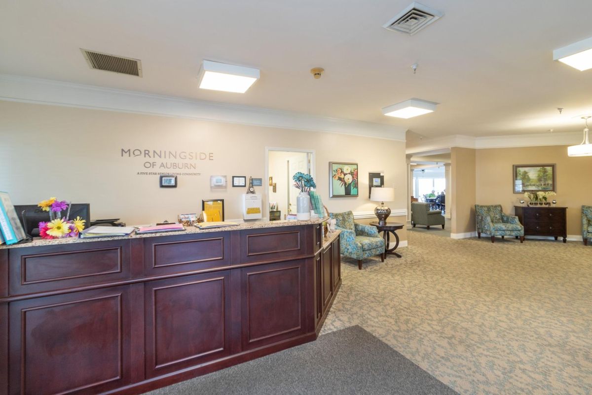 A reception area with a wooden desk and seating in an office environment.