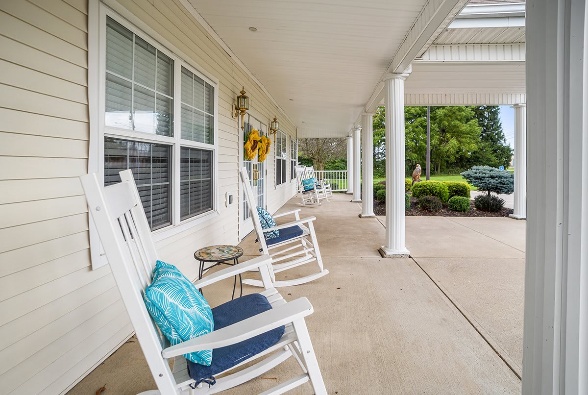 A welcoming front porch with white rocking chairs and decorative pillows.