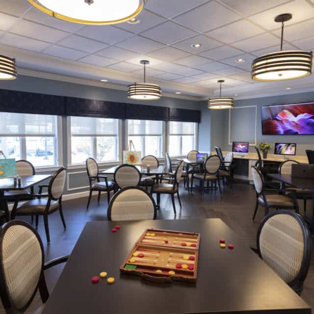 A cozy game room with tables, chairs, and a backgammon board ready for play.