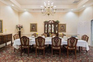 An elegantly decorated dining room with a large table and ornate chairs under a chandelier.