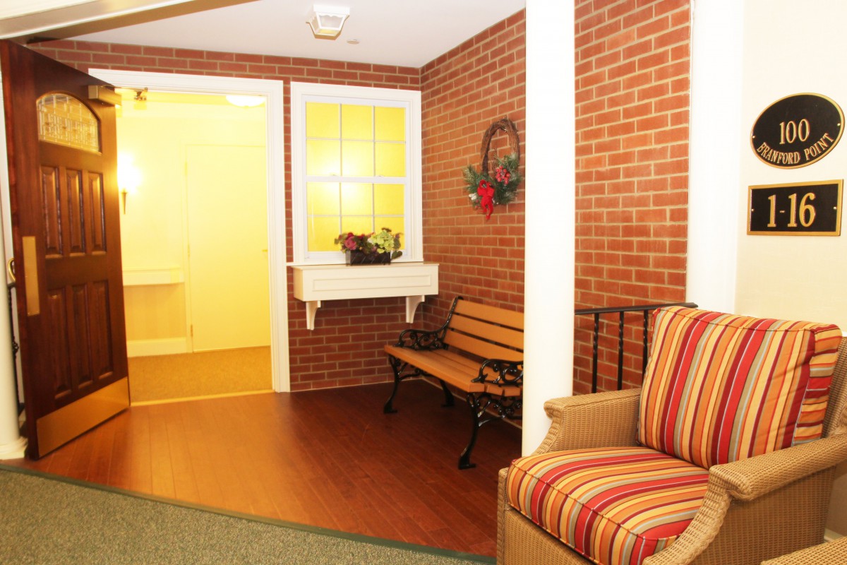 A cozy interior space with a brick wall, featuring a bench and a striped sofa.