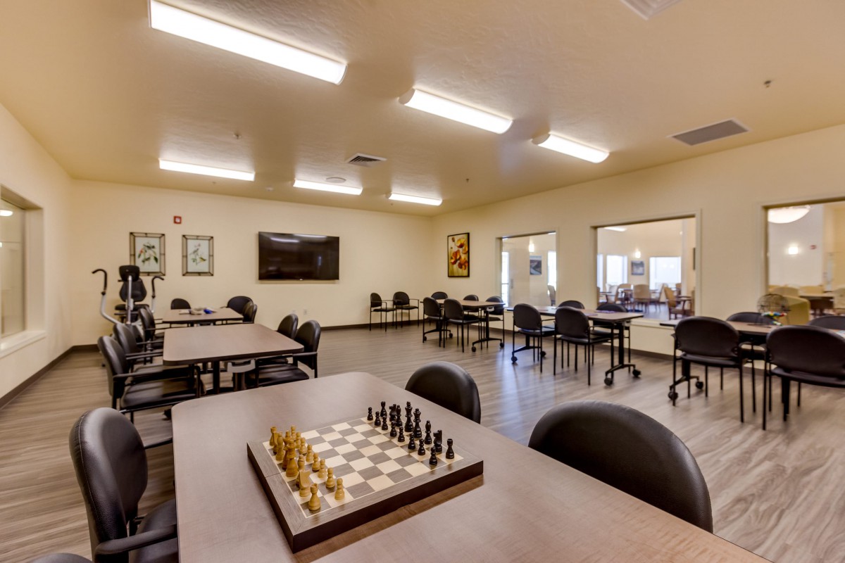 A classroom setting featuring tables and chairs, with a chess board set up in the foreground.
