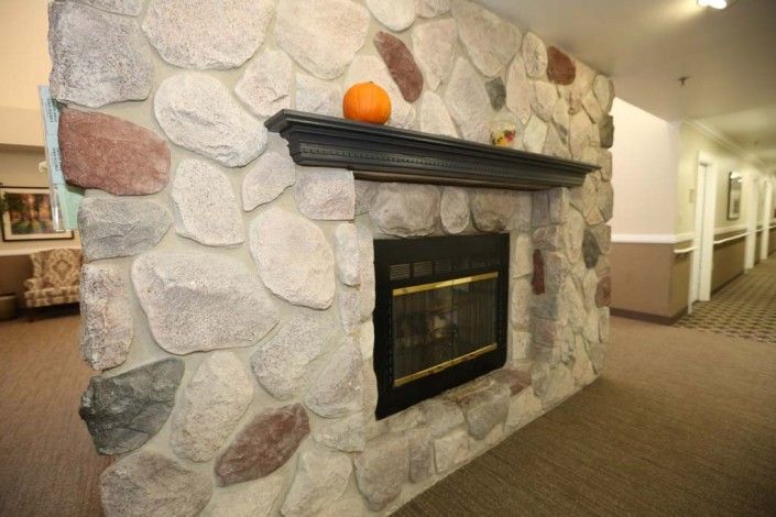 A cozy stone fireplace with a pumpkin on the mantel, adding a touch of autumn decor.