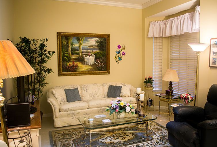 A cozy living room with a cream sofa, decorative painting, glass coffee table, and soft lighting.
