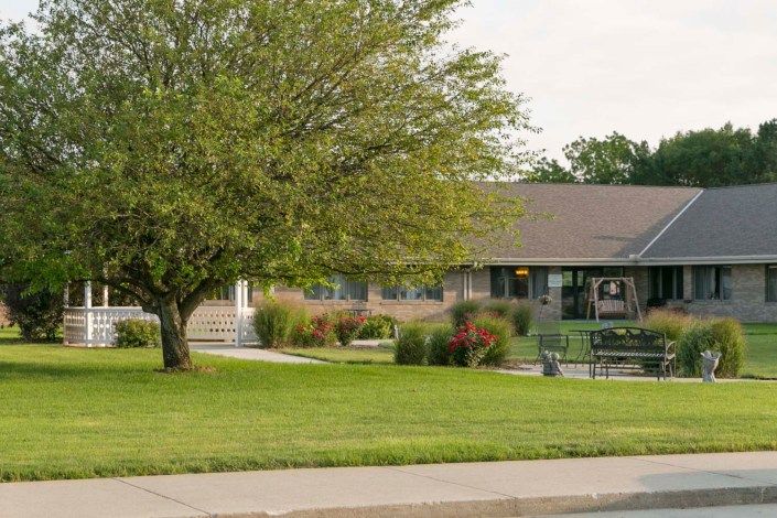 A suburban house with a large tree and well-maintained lawn.