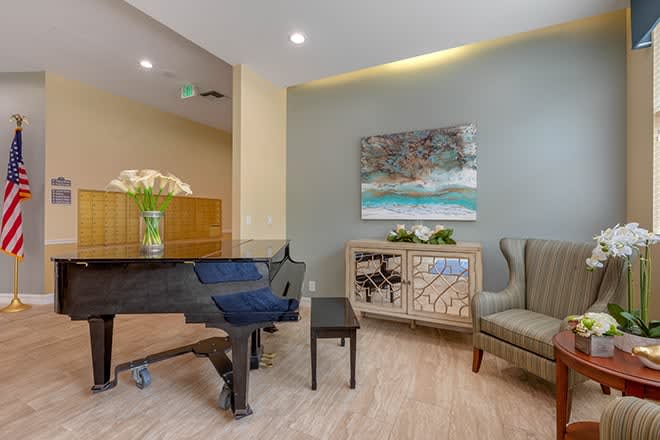 A modern living room featuring a grand piano, stylish furniture, and elegant artwork on the wall.