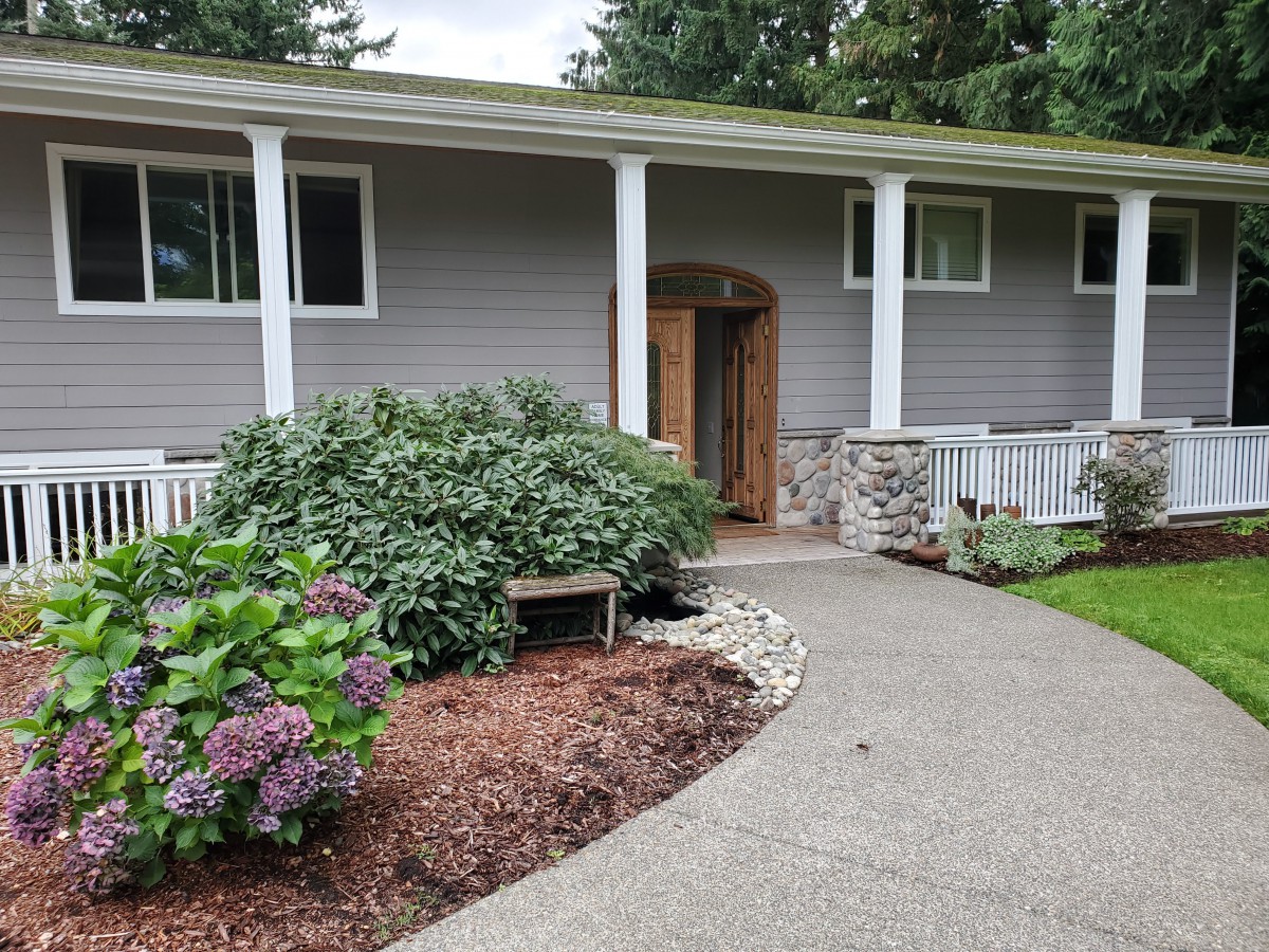 A cozy house entrance with a landscaped garden and curved pathway.