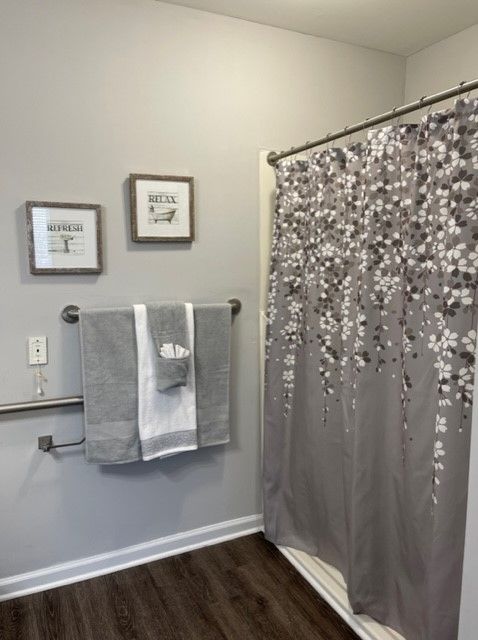 A stylish bathroom featuring a floral shower curtain and neatly arranged towels with wall art.
