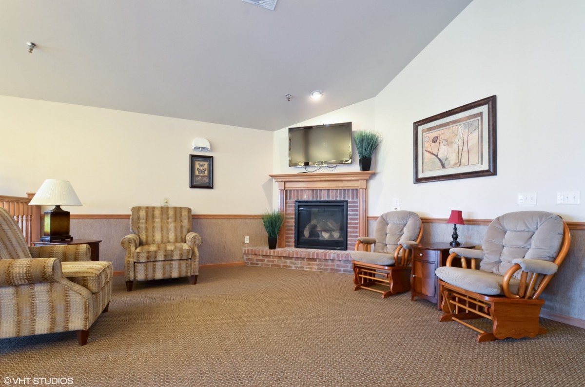 A cozy living room with armchairs, a fireplace, and a television.