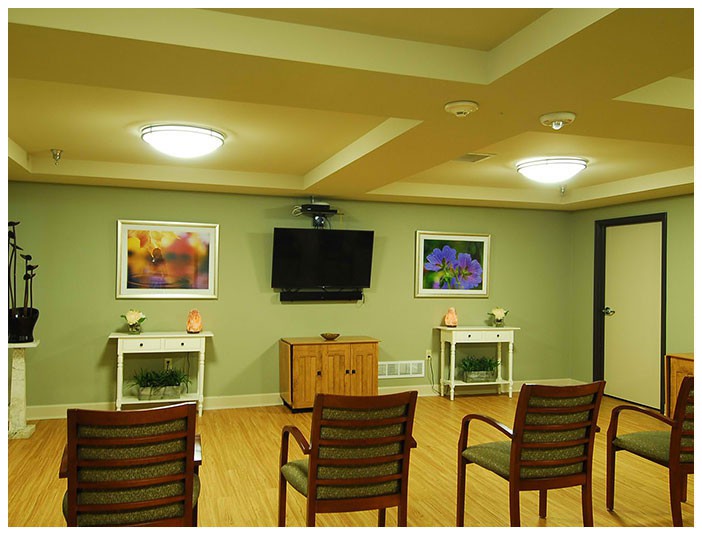 A well-lit conference room with chairs arranged facing a wall-mounted television and colorful artwork.