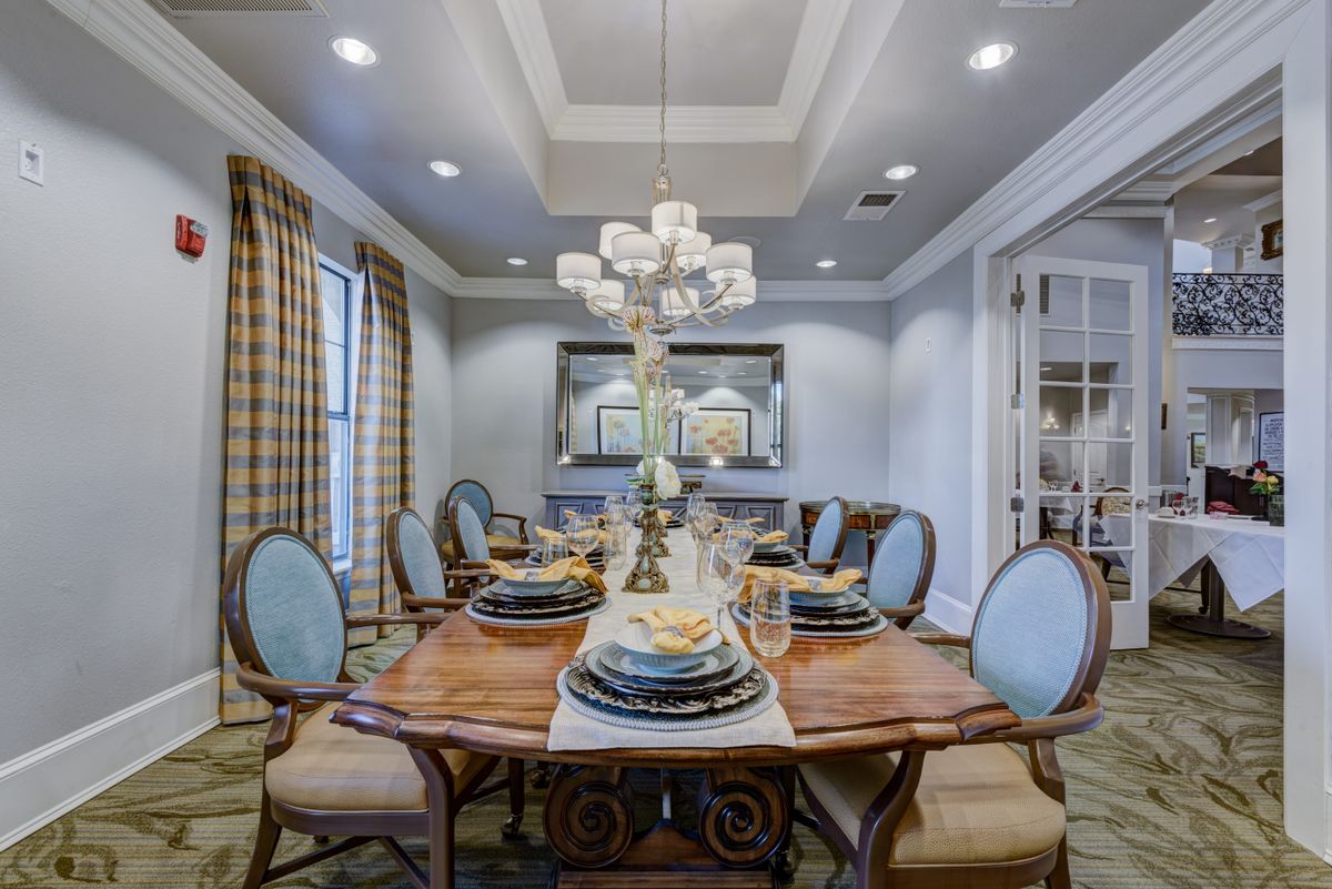 An elegantly designed dining room with a central chandelier and ornate table settings.