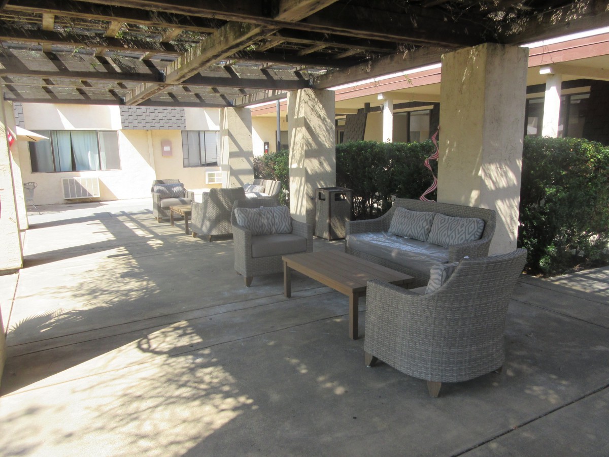 Outdoor patio with chairs and table under a pergola.