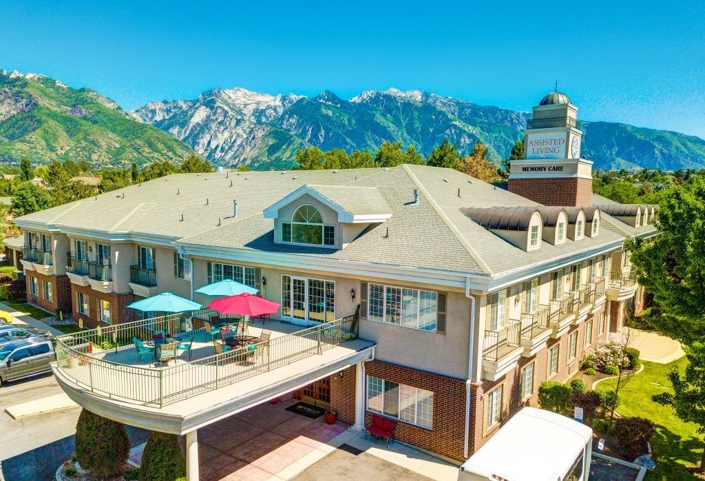 A scenic view of a building with a rooftop deck and mountains in the background on a sunny day.