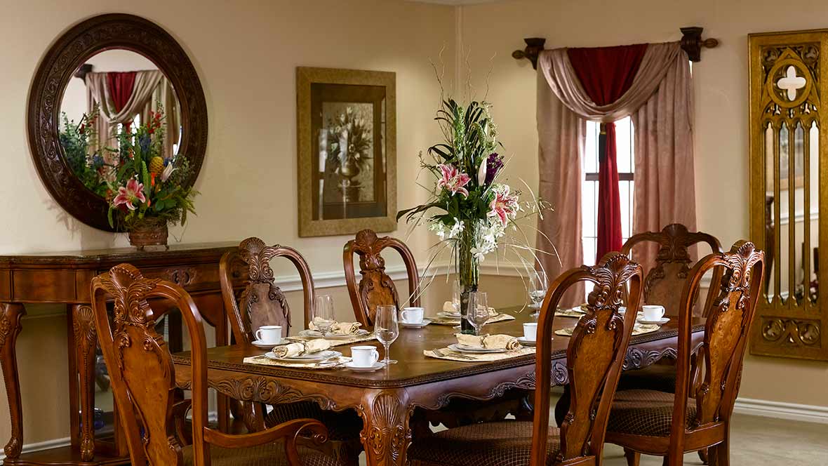 Elegantly set dining table with floral centerpiece in a warmly decorated room.