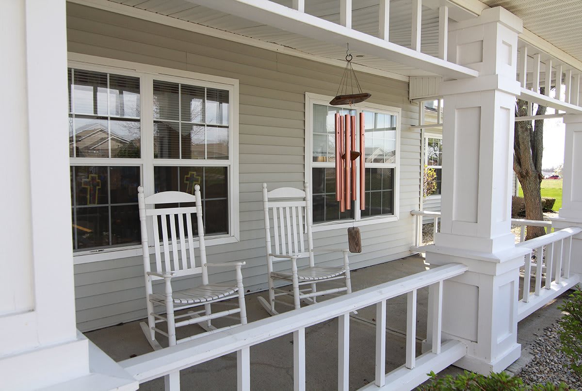 A cozy front porch with two white rocking chairs and a wind chime.
