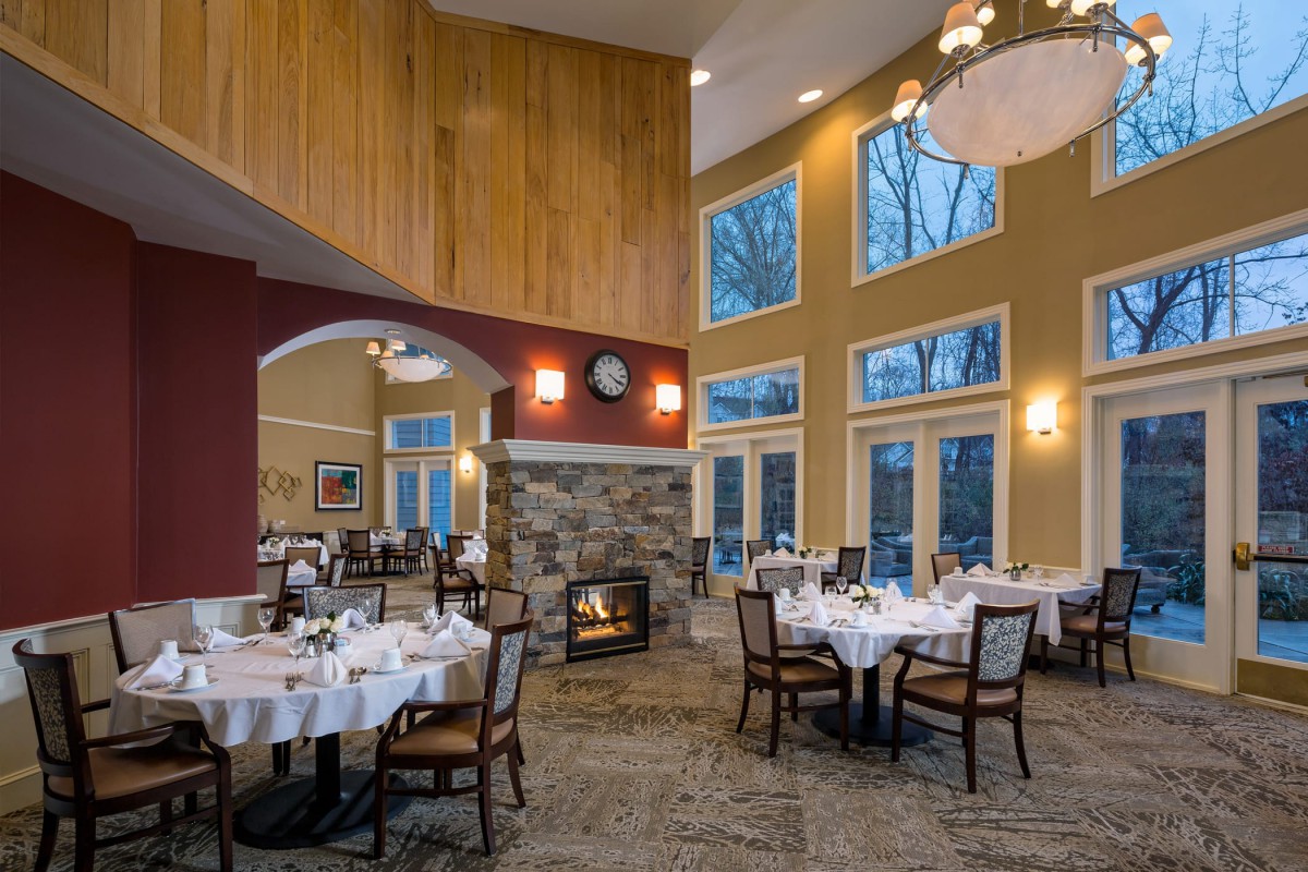 Elegant restaurant interior with a cozy fireplace and large windows.