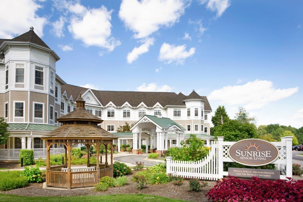 A scenic view of a hotel building with a gazebo and landscaped garden under a blue sky.