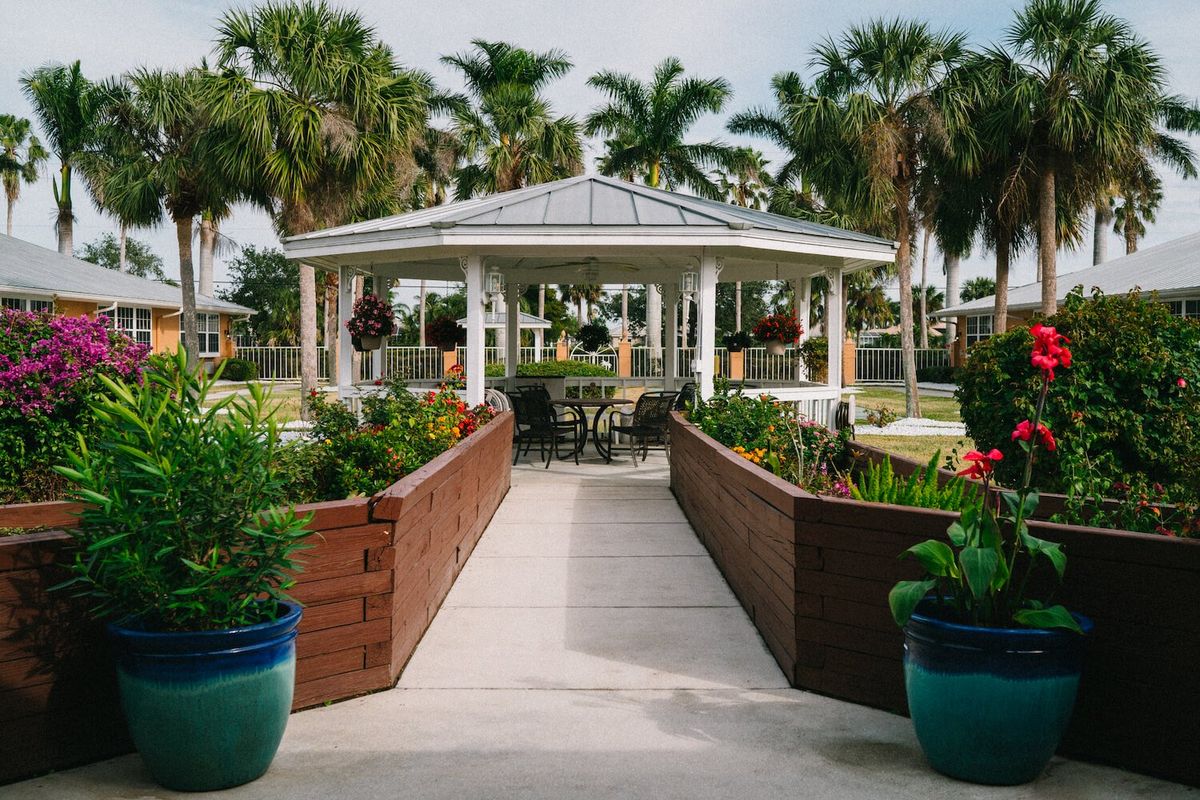 A picturesque gazebo surrounded by lush gardens and palm trees.