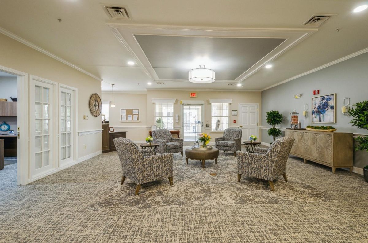 A spacious and elegantly designed lobby area featuring a central seating arrangement with patterned chairs and a modern lighting fixture.