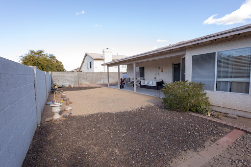 A spacious backyard patio area with gravel and a view of the house.