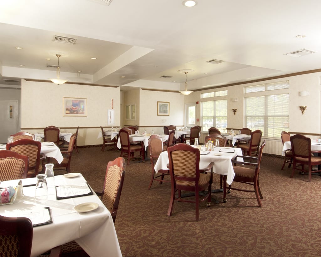 A neatly arranged dining room with multiple tables and chairs, ready for guests.