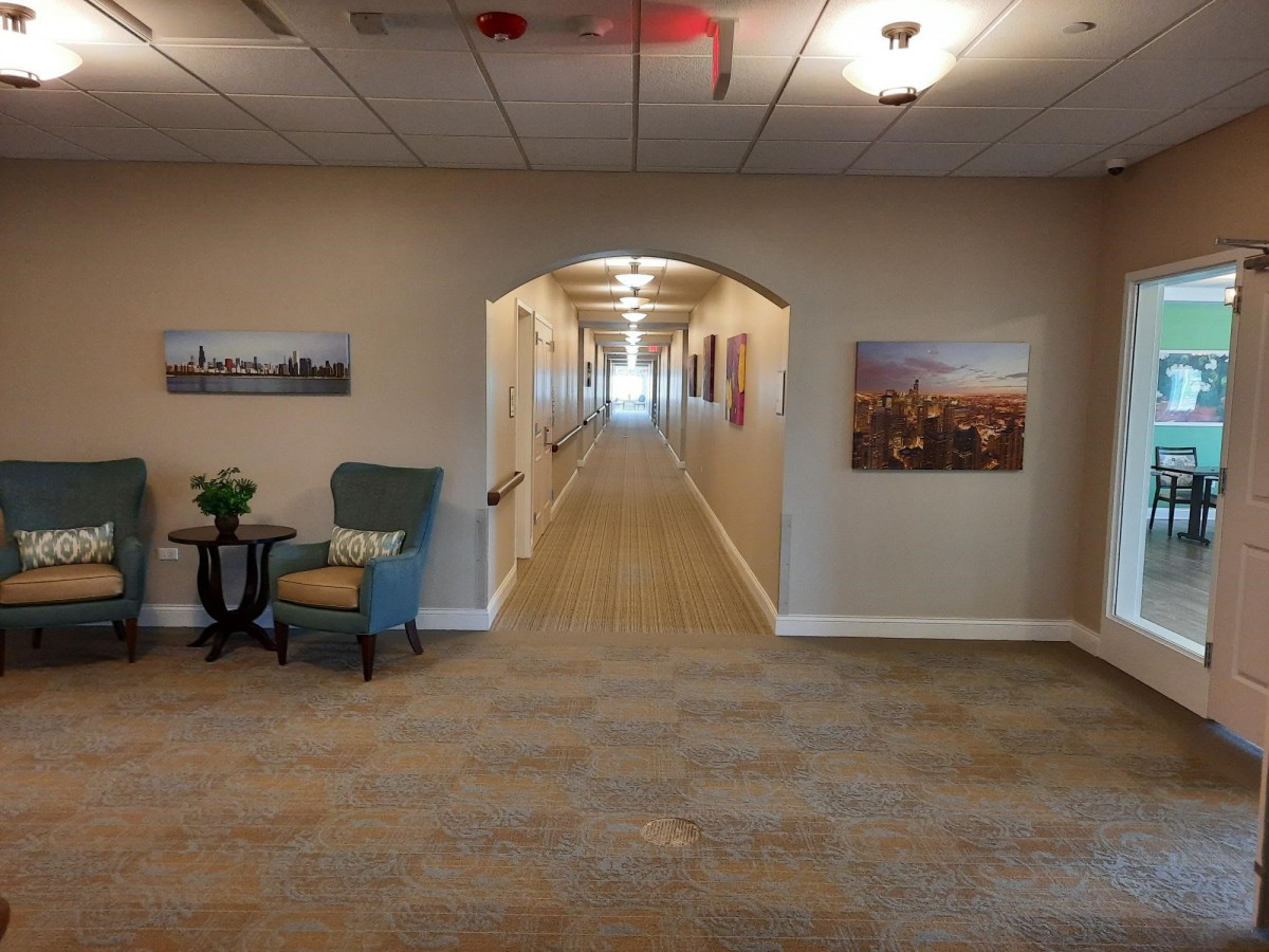 A well-lit hallway with chairs and artwork on the walls.